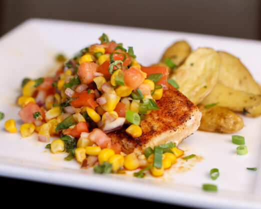 a white plate topped with a piece of meat covered in veggies